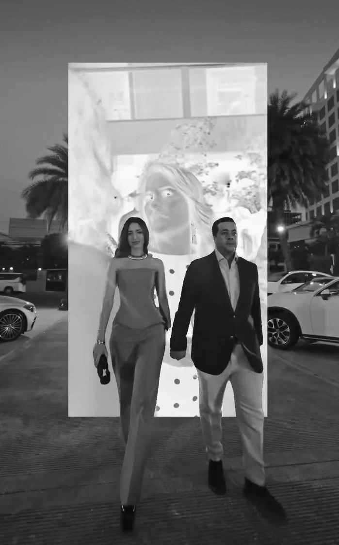 Pareja caminando frente a pantalla con efecto visual en evento nocturno