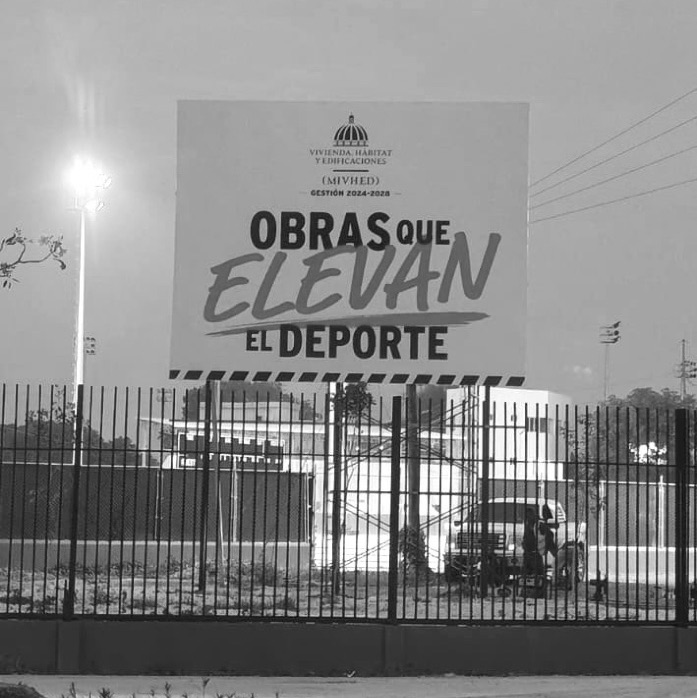 Valla del MIVEHD Obras que elevan el deporte, iluminada al anochecer