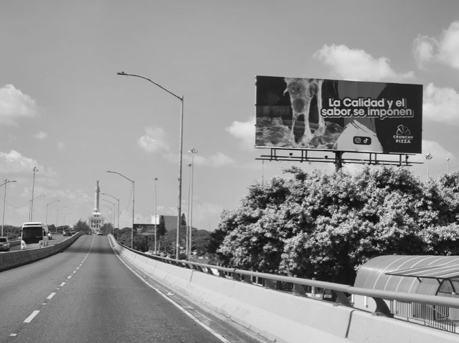 Valla sobre la autopista en Santiago, con el Monumento al fondo